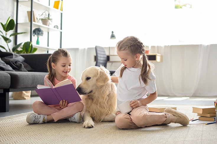 Little sisters with books and golden retriever dog